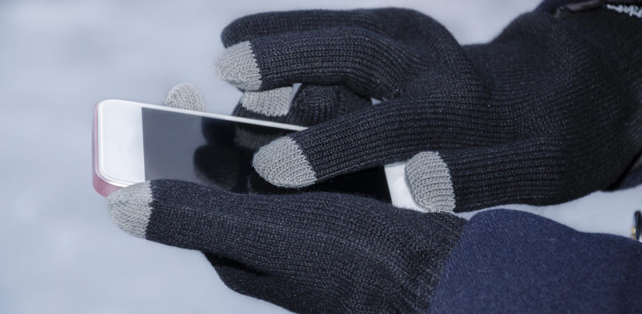 Girl's hands, in special gloves for typing on a gadget in winter, close-up